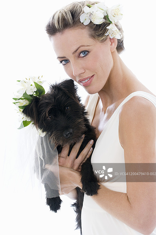 新娘抱着戴着鲜花的狗的肖像图片素材