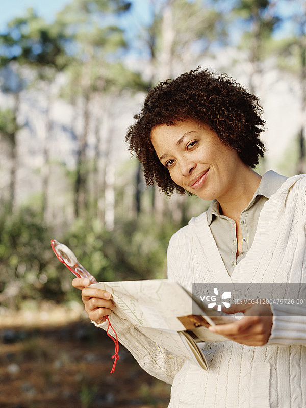 女人在森林中手持指南针和地图图片素材