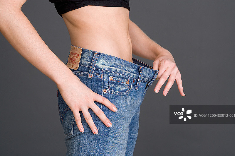 女人拿着宽松的牛仔裤腰带，中部图片素材