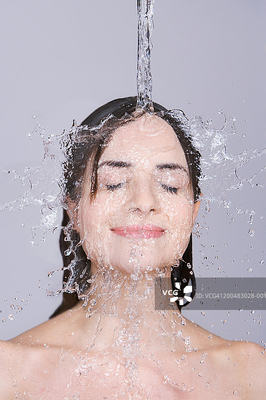 水浇在年轻女人的脸上和头发上，特写图片素材