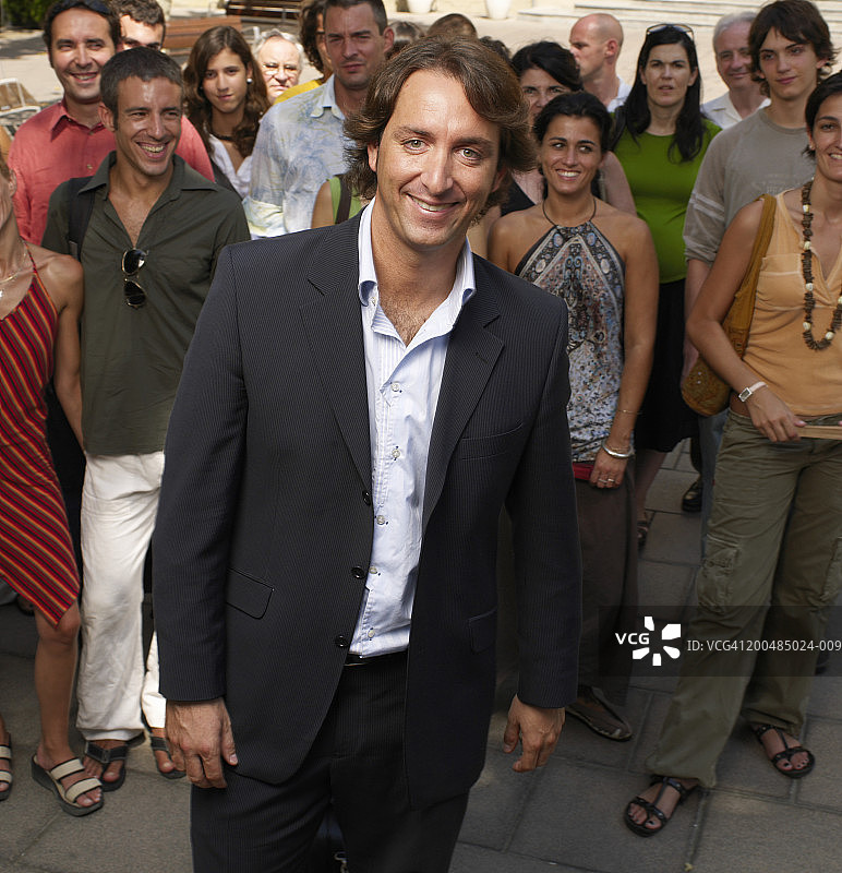 商人站在人群中微笑，肖像图片素材