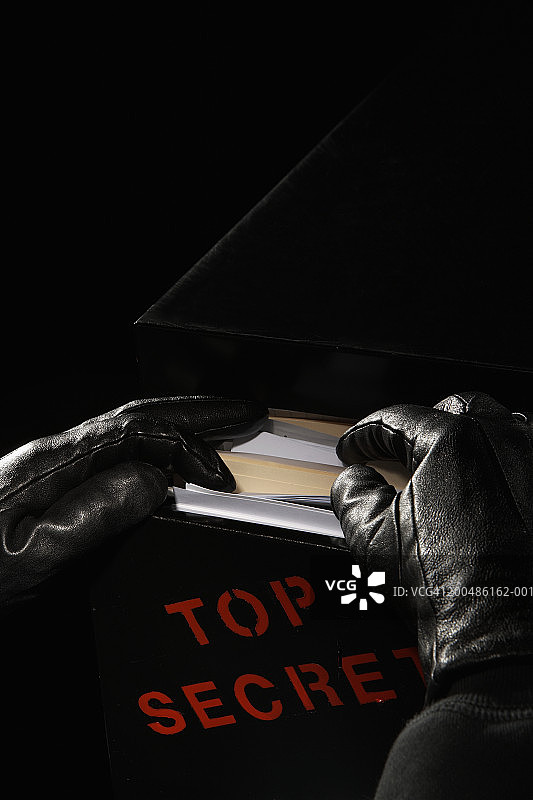 戴着皮手套的人在标有“绝密”的档案柜里寻找图片素材
