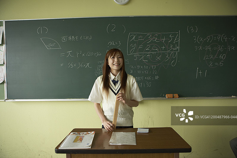 在老师的桌子旁微笑的女青少年学生（17-19岁）图片素材