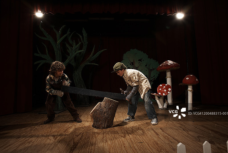 在舞台上扮演伐木工人，锯树桩的两个男孩图片素材