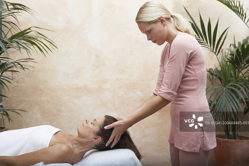 中年妇女闭着眼睛享受头部按摩图片素材