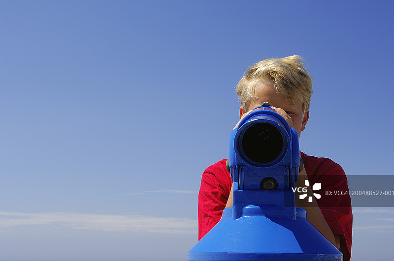 男孩（12-14岁）正在使用投币式望远镜观看，肖像照图片素材