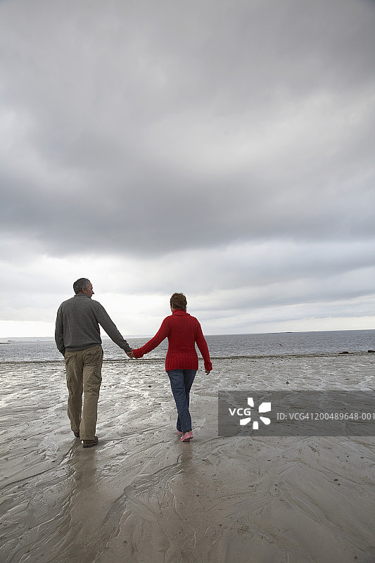 中年夫妇牵手在海滩上散步，背影图片素材