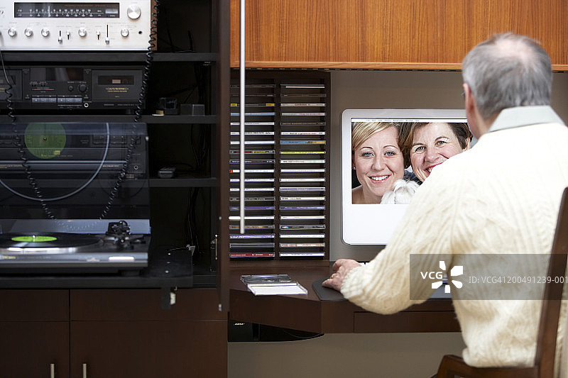 年长的男人在电脑上看家庭照片，后视图图片素材