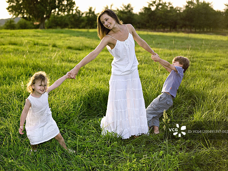 在田野里拉着母亲微笑的儿童（3-6岁）图片素材