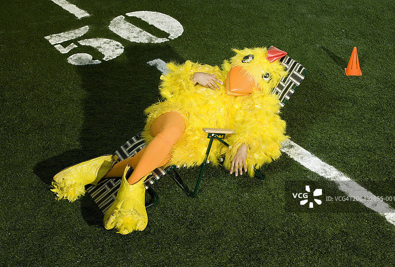美式橄榄球：黄色小鸟吉祥物在球场日光浴躺椅上图片素材
