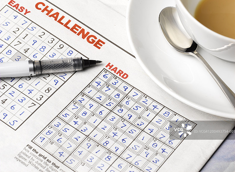 报纸上的数独，配有茶杯和钢笔，特写图片素材