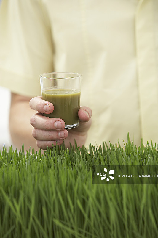 拿着一杯小麦草汁的男人，中间部分图片素材