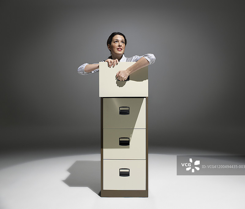 聚光灯下，女商人从文件柜里爬出来图片素材