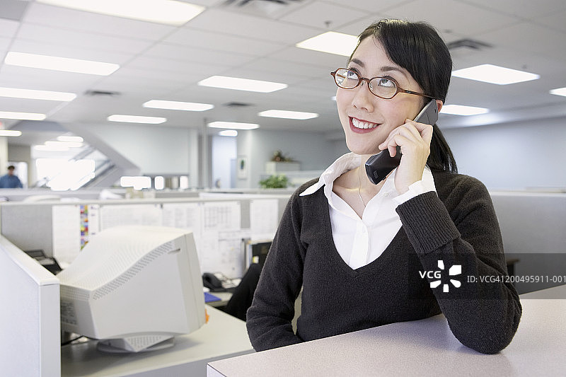 在办公室用手机向上看的年轻女商人图片素材