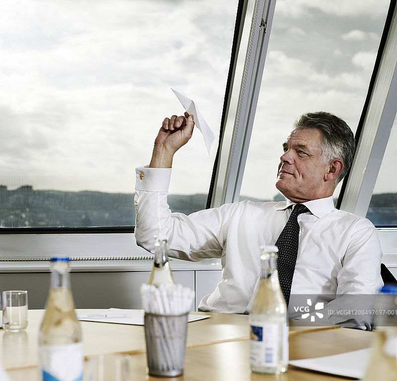 商人于办公室窗口抛掷纸飞机图片素材