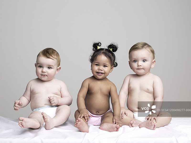 女婴和两个男婴（6-9个月）坐着，肖像照图片素材