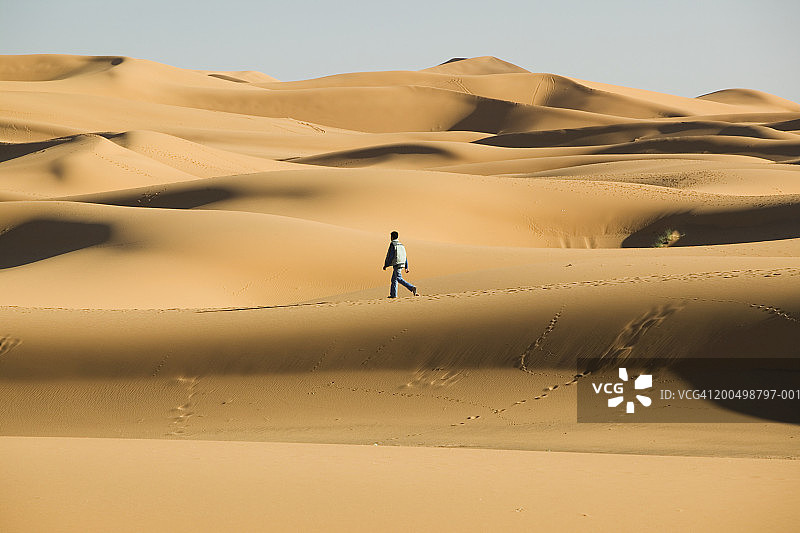 摩洛哥塔菲拉勒特，男子在Erg Chebbi沙丘上行走图片素材