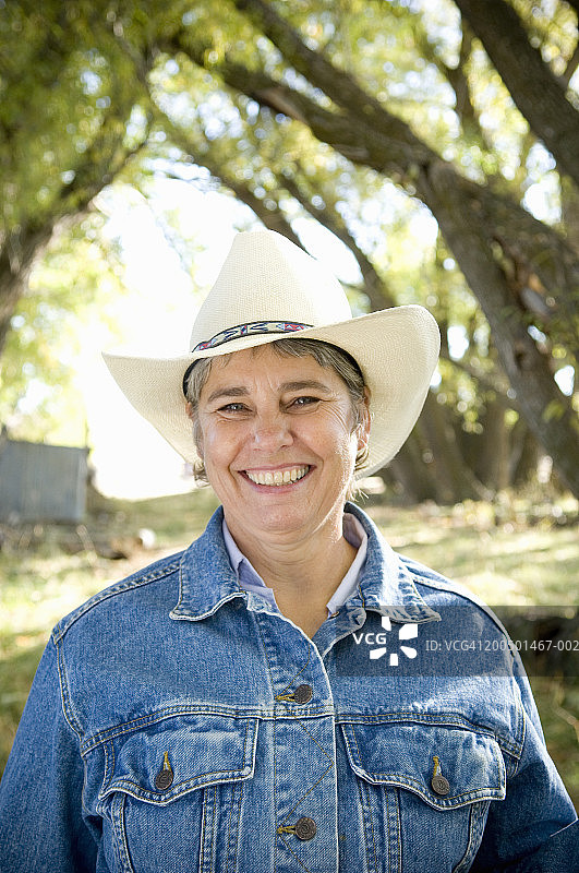 戴牛仔帽和牛仔夹克的微笑女牧场主肖像图片素材