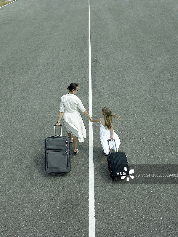 母女（5-7岁）在跑道上拉着行李，后视图图片素材