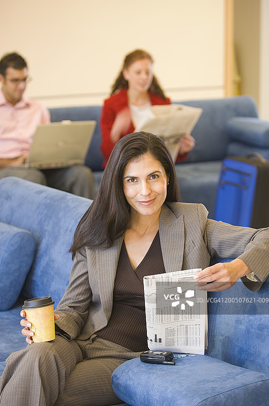 拿着报纸和咖啡，面带微笑的中年妇女肖像图片素材