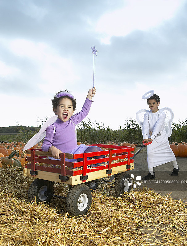 穿着天使服装的男孩（6-8岁）拉着穿着仙女服装的女孩图片素材