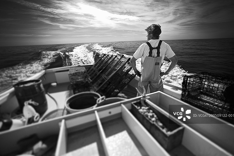 渔民站在船上面朝大海的背面（黑白照片）图片素材