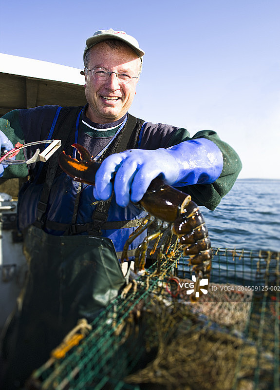 微笑着举龙虾的渔民肖像图片素材