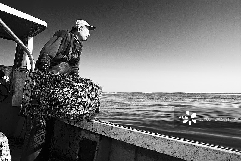 渔民在船边拿着龙虾陷阱（黑白照片）图片素材