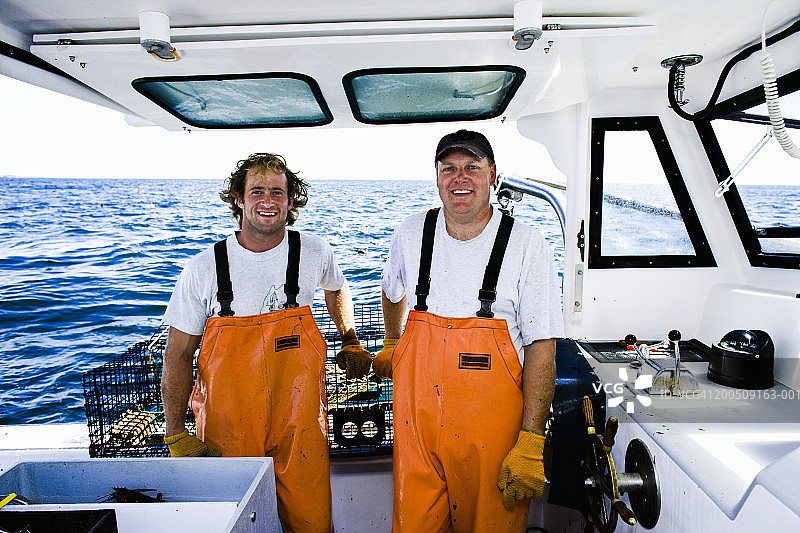 海上船上微笑的两名捕龙虾渔民肖像图片素材