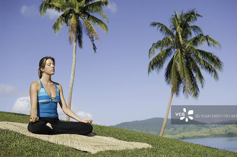 斐济瓦努阿岛：在山坡上练习瑜伽的年轻女人图片素材