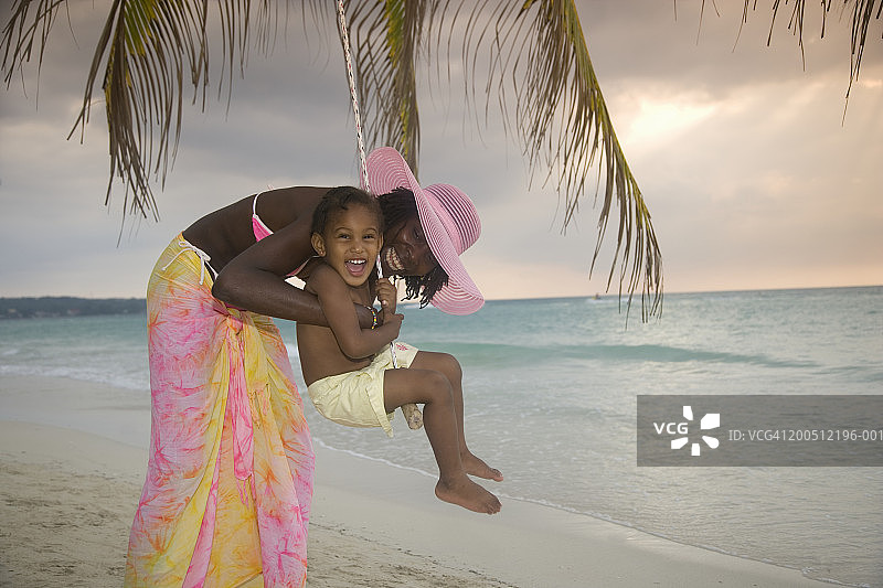 母亲和女儿（3-5岁）在日落时玩秋千图片素材