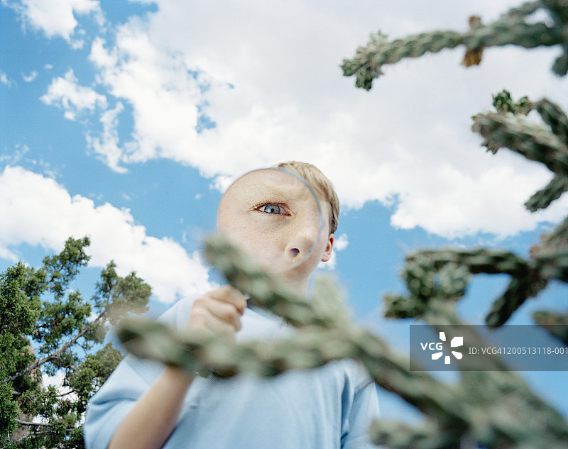男孩户外通过放大镜观察肖像图片素材