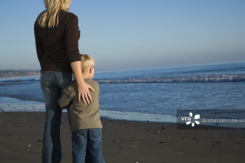 夕阳下，母子（2-4岁）站在海滩上，后视图图片素材