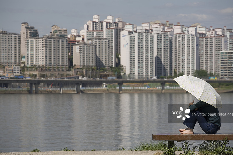 韩国首尔，一名女子坐在汉江公园的长椅上图片素材