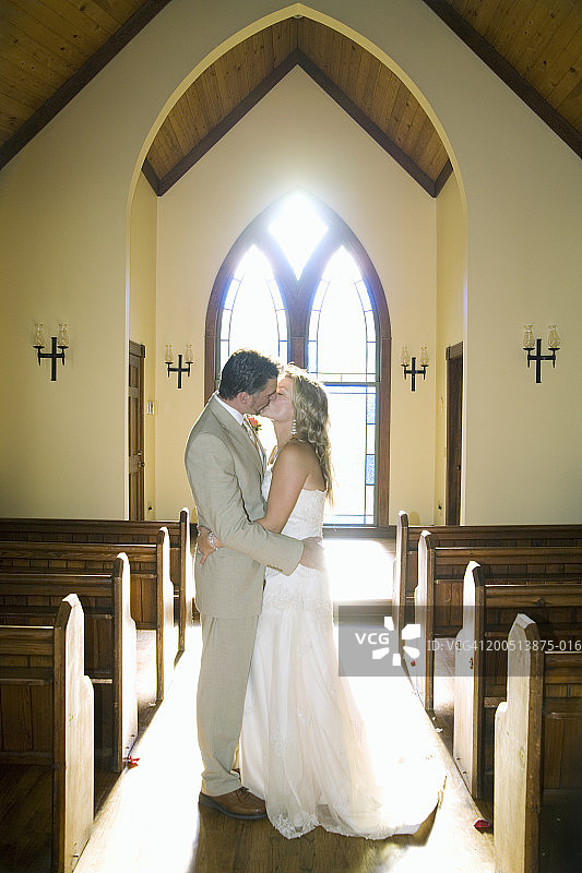 在教堂里亲吻的新娘和新郎（侧视图）图片素材
