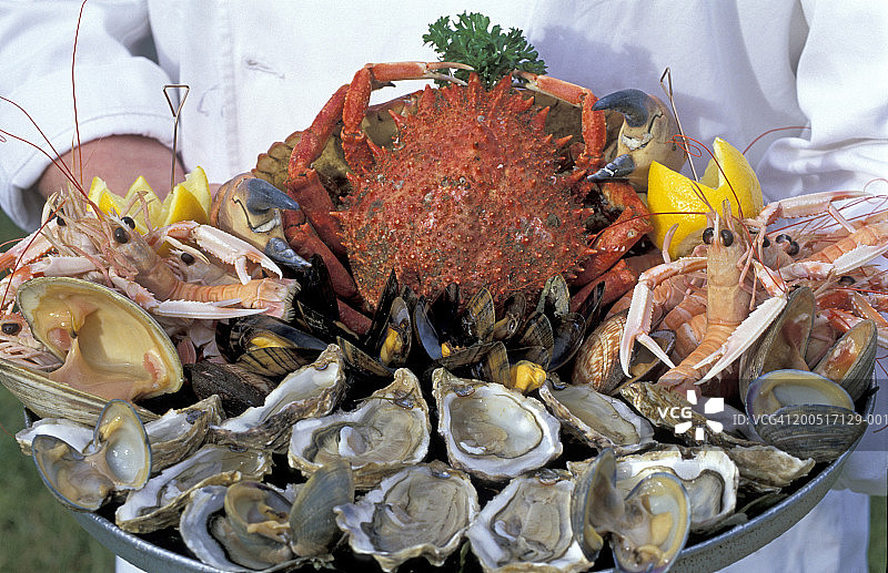 男人端着海鲜托盘，特写图片素材