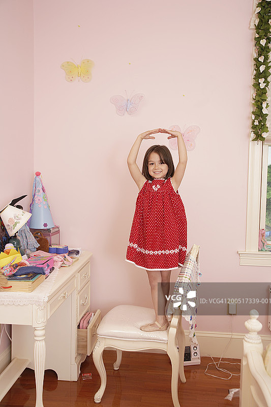 女孩（5-7岁）站在卧室的椅子上，摆出芭蕾舞姿图片素材