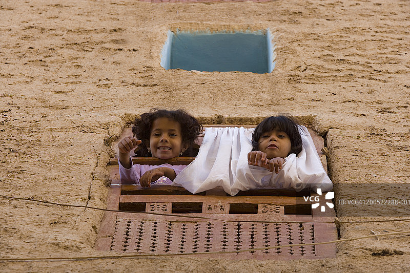 也门：倚窗微笑的男孩和女孩（6-8岁）肖像图片素材