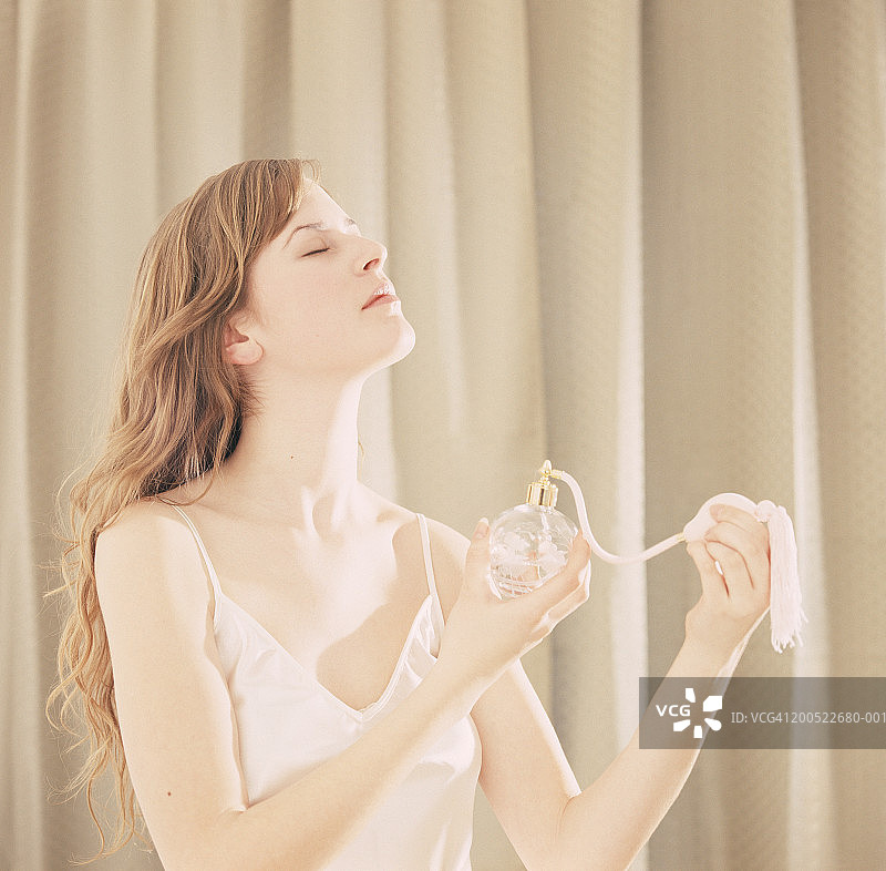 年轻女人喷香水，侧视图图片素材