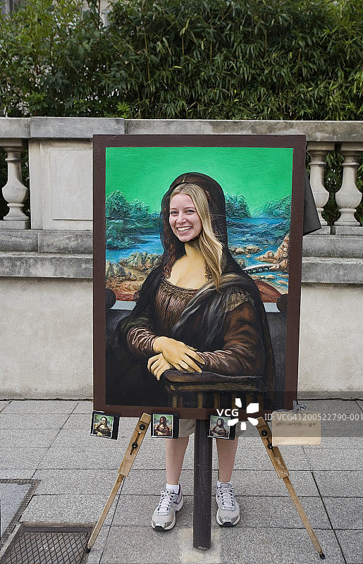 法国巴黎：年轻女子在蒙娜丽莎画板后摆姿势图片素材
