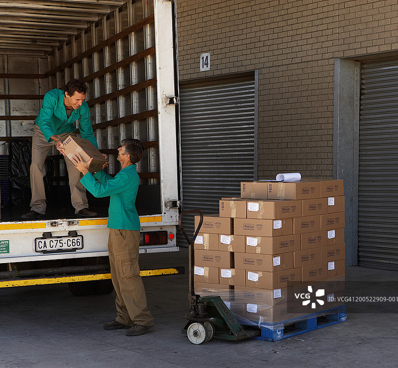 两名男子将箱子从托盘装入卡车图片素材