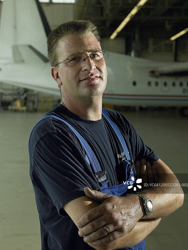 站在飞机库中飞机前的修理工肖像图片素材