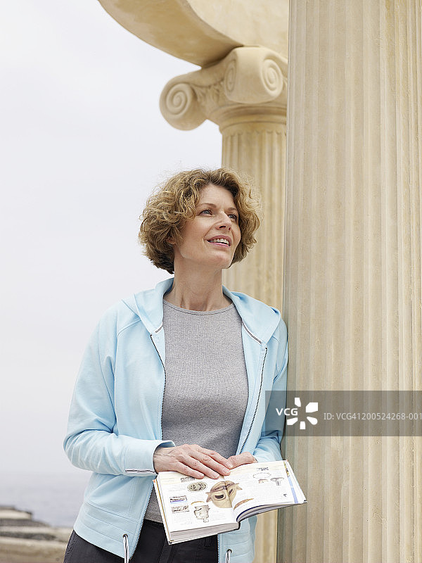 靠在柱子上，拿着指南的女人图片素材