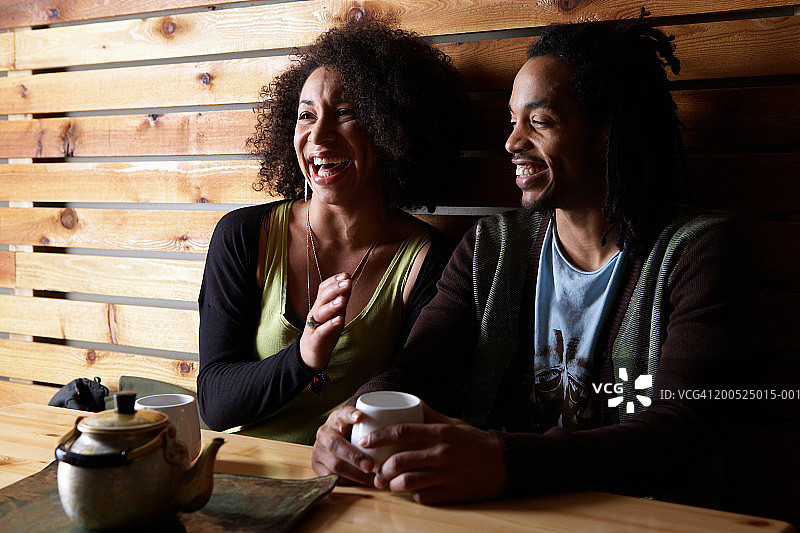 在咖啡馆的桌旁喝茶、欢笑的男人和女人图片素材