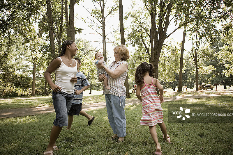 （6-12岁）儿童围绕着抱着男婴的祖母跑圈图片素材