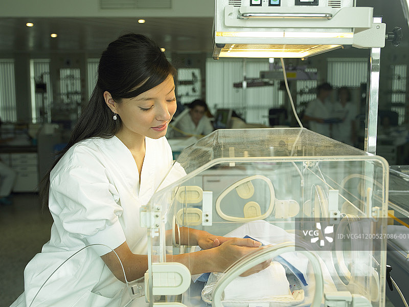 女护士在医院的保育箱里照顾婴儿图片素材