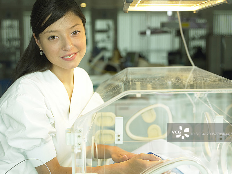 在医院抱着保温箱里婴儿的女护士肖像图片素材