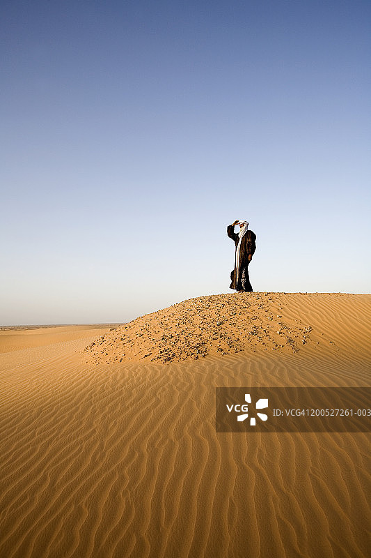 尼日尔撒哈拉沙漠南部：图阿雷格男子站在沙漠中遮阳图片素材