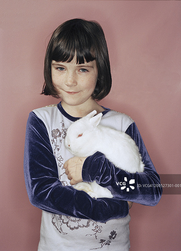 抱着白色兔子微笑的女孩肖像（8-9岁）图片素材