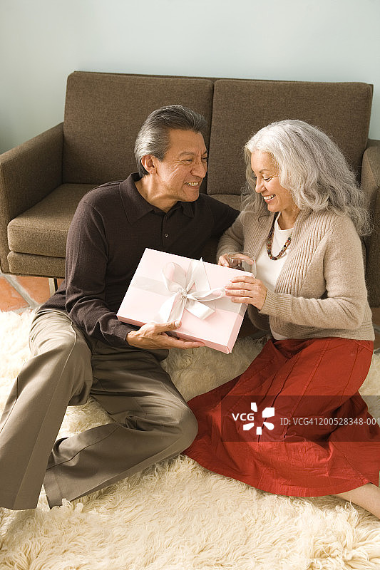 中年夫妇坐在休息室地板上交换圣诞礼物图片素材